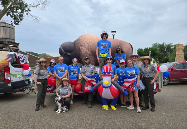 Group of people in patriotic clothing posing in front of a large inflatable bison.